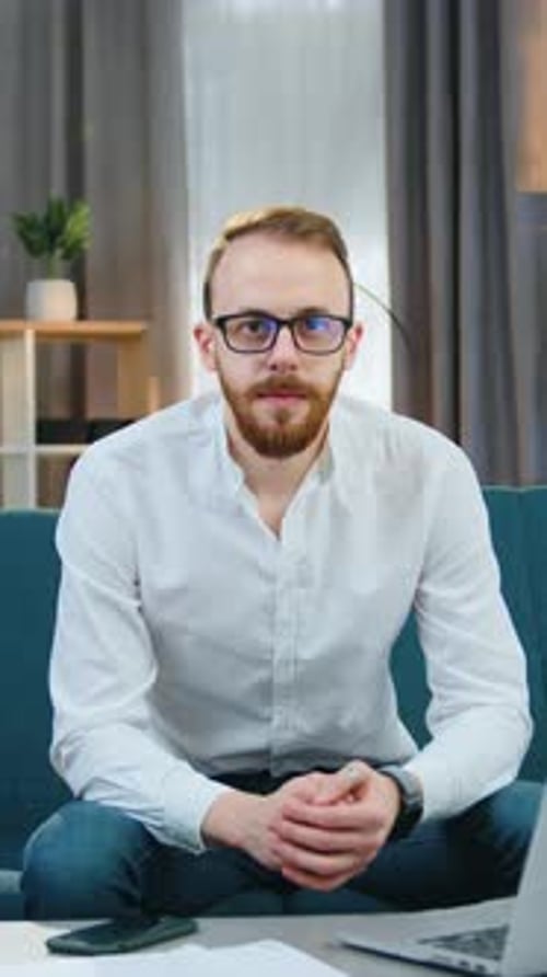 Man in White Shirt Sits and Looks at Camera