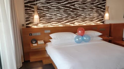 Balloon Decor Over Bed With Pure White Linen Beddings In A Hotel Room. Pan Right Shot