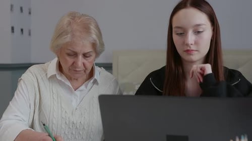 Senior Adult Working On Computer With Young Adult