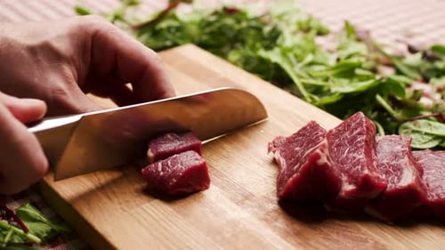 Hand Cuts Raw Meat on Board Close Up