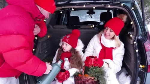 Family - father, mother and daughter cheerfully celebrate Christmas in the forest