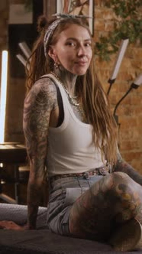 Vertical Portrait of Young Girl with Full Body Tattoo Posing in Modern Studio