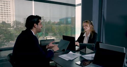 Young businessman talking to smiling female colleague during office discussion. Collaborative