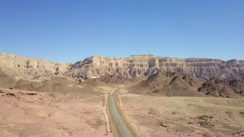 Empty desert road with mountains and blue sky in the background