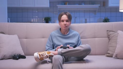 Young Adult Plays Handheld Video Game on Sofa