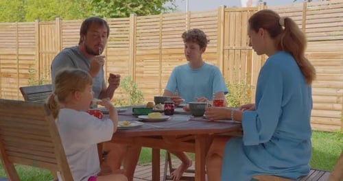 Family Enjoying Breakfast Together in the Backyard