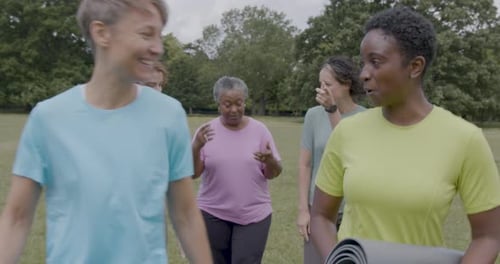 Group of Women Walking Outdoors in Public Park Carrying Exercise Mat