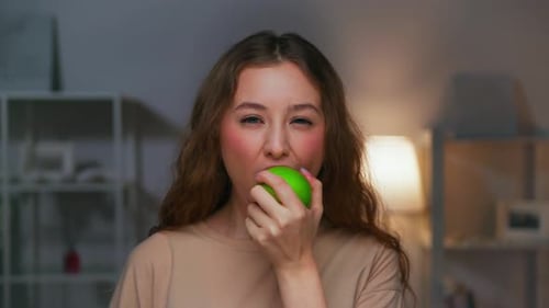 Portrait of Young Woman Eating Healthy Food of Green Apple and Looking at Camera