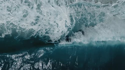 Cinematic Aerial Slow Motion of Sea Waves Rolling Onto Wet Sand Dynamic White Foam and Deep Blue Sea