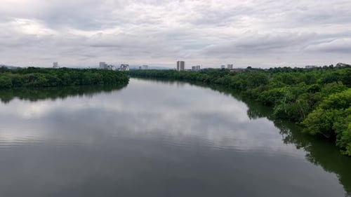 Serene River Landscape with Lush Greenery and Urban Skyline at Sungai Melayu