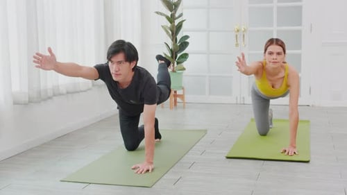 Man and Woman Practicing Yoga Inside Bright Room
