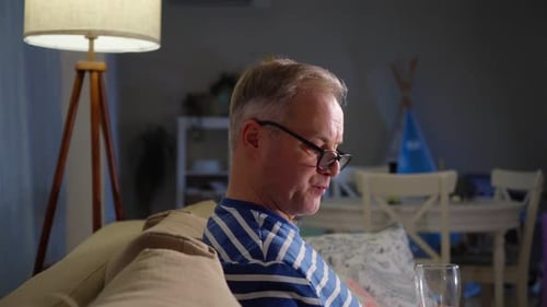 Man Relaxing on Couch Drinking Beverage at Home