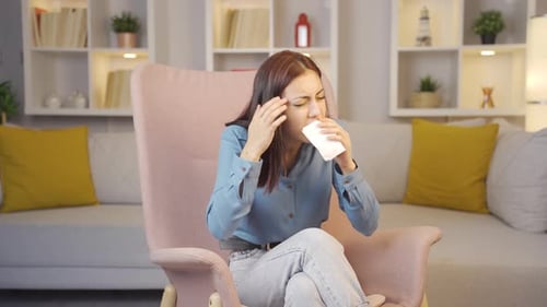 Young Woman Coughing into Tissue in Living Room
