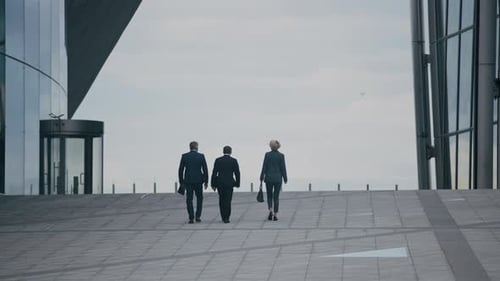 Business Partners Going across City Square with Glass Office Buildings