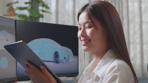 Close Up Of Asian Female Automotive Designer Comparing The 3D Model Of Ev Car On Computer
