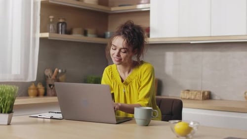 Woman Typing on Laptop in Kitchen at Home