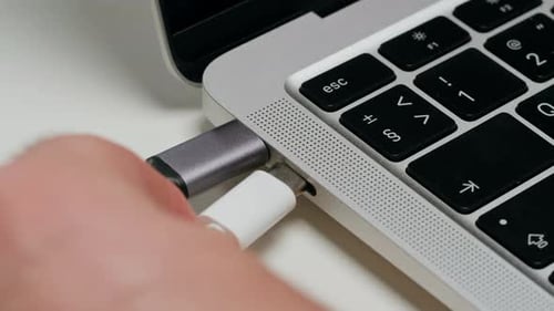 Ladeanschluss zum Laptop auf weißem Tisch, Nahaufnahme, Telefon, Ladeanschluss, USB-Kabel für Geräte
