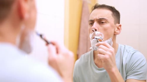 Homem raspando a barba no espelho do banheiro