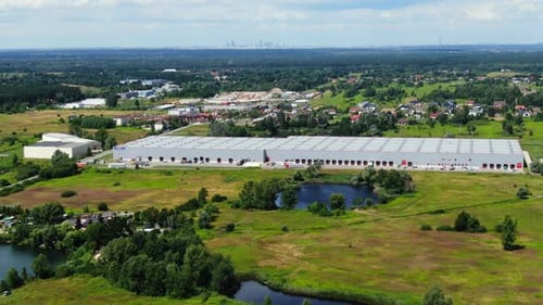 Aerial View of Large Logistics Warehouse in Green Rural Landscape