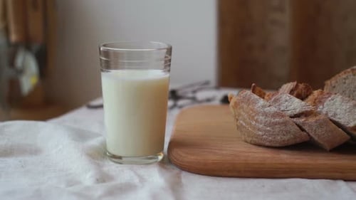 Vaso de leche y rebanada de pan sobre tabla de madera. Taza de leche y