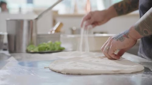 Hands of Chef Stretching Dough for Pizza Base on Kitchen Table