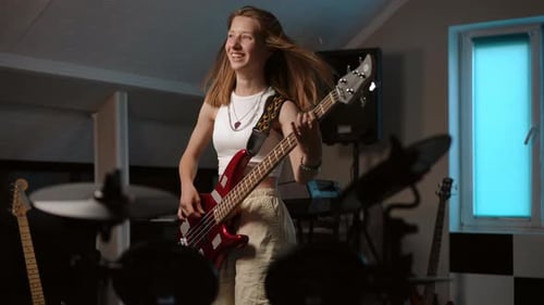 Woman Plays Bass Guitar in Music Room