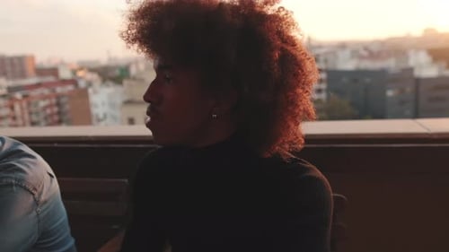 Nahaufnahme eines jungen Mannes, der auf der Terrasse sitzt und mit Freunden spricht