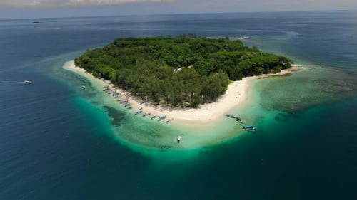 Pull back aerial drone shot flying away from a tropical island in the ocean.