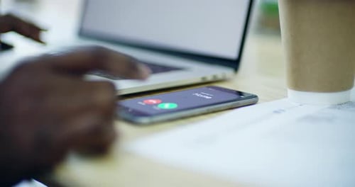 Hand types on laptop as phone receives call