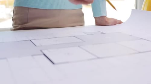Businesswoman reviews architectural blueprint design in modern office workplace