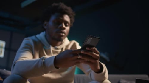Man Using Smartphone in Dimly Lit Room