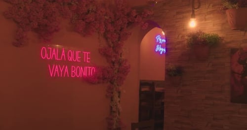 Beautiful general shot of a Mexican restaurant area decorated with a led sign containing a phrase fr