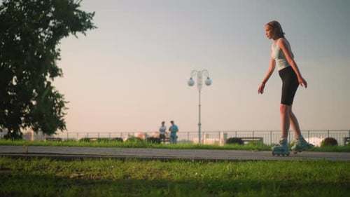Young Lady Roller Skating Outdoors in Park with Cityscape and Lush Greenery in Background