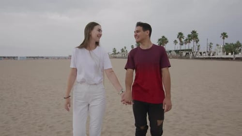 Happy Romantic Young Teen Caucasian Couple Walking Holding Hands on Sand Beach