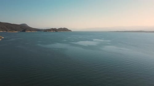 Aerial drone flying over a lake, water dam, with mountains at sunrise. Beautifull dreamy landscape v