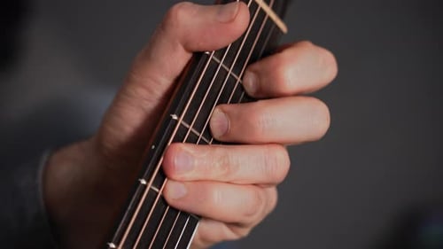Closeup of a Man Playing an Acoustic Guitar The Frame Shows the Fretboard and the Musician's Hand