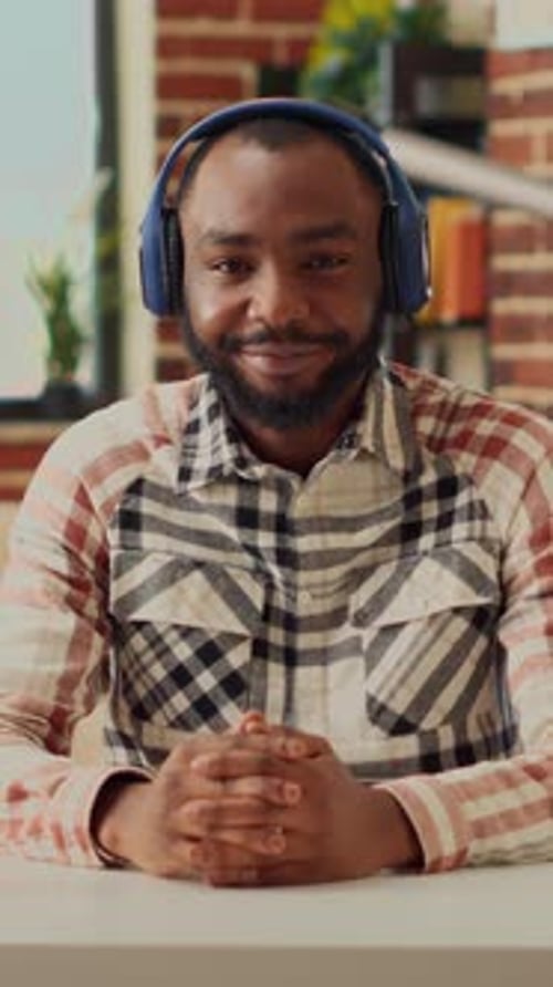 Man in Headphones Talking at Desk Indoors