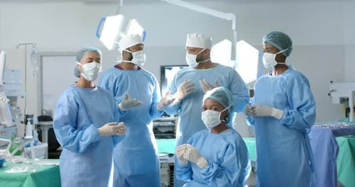 Portrait of diverse surgeons wearing surgical gowns in operating theatre, slow motion