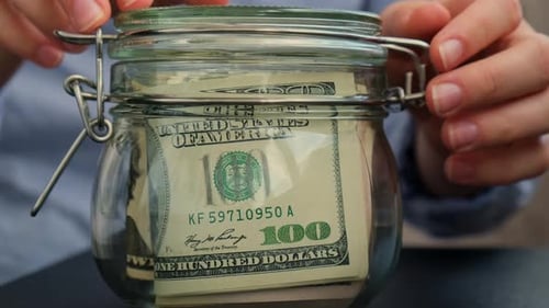 Unerkennbare Frau spart Geld in einem mit Dollar-Banknoten gefüllten Glasgefäß INVESTITION