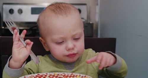 Infant Eating Meal with Fork in Home Kitchen
