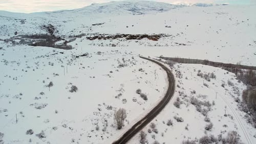 Aerial View of Snowy Road and River in Winter Mountain Landscape