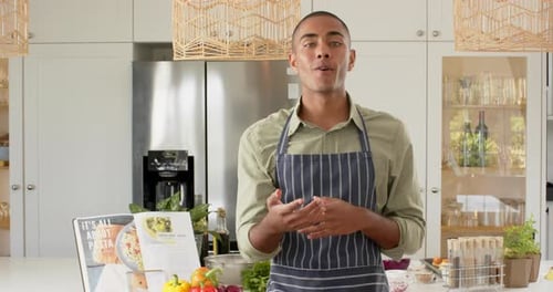 Vlogger de cuisine biracial en tablier parlant et filmant dans la cuisine