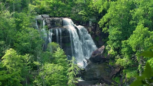 Whitewater Falls with Falling Down Clear Water From Rocky Boulders Between Green Lush Woods in