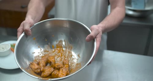 Male Chef Tossing Chicken Wings in Buffalo Sauce Closeup in Ultra Slow