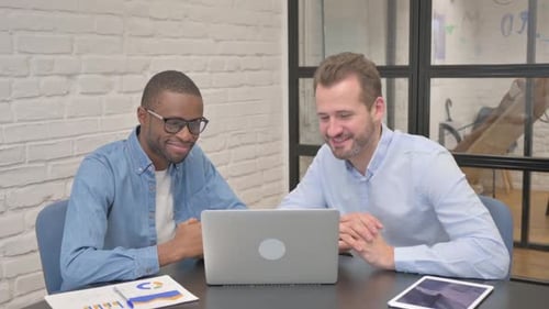 Two Men Working Together on Laptop in Office