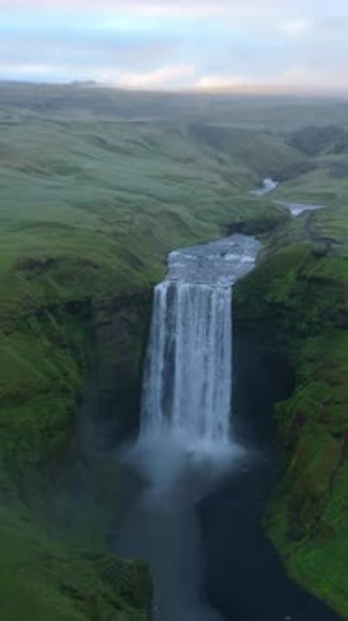 Sweeping Aerial View of Icelandic Waterfall Amid Lush Greenery and Flowing River