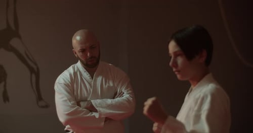 Karate Instructor Guides Young Student Repeating Kicks in Gym