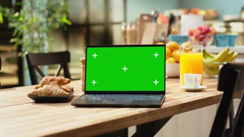 Green Screen Laptop on Wooden Table in Empty Bright Kitchen