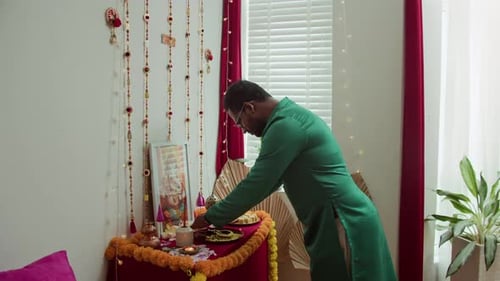 Man Offering Prayers at a Decorated Home Shrine
