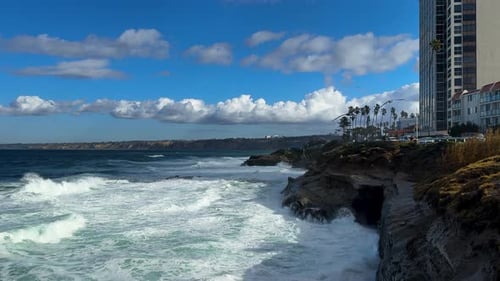 King tide at La Jolla Cove skyline view over waves crashing on clliffs birds flying by..